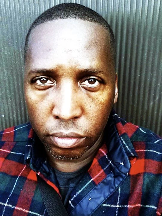 Portrait of Marvin K. White wearing a red and navy plaid shirt.